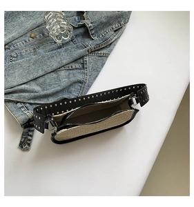 Détail du sac bandoulière en paille tissée avec bandoulière cloutée et fermeture éclair