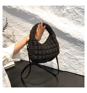 Detail showing black quilted crossbody tote bag texture and detachable shoulder strap
