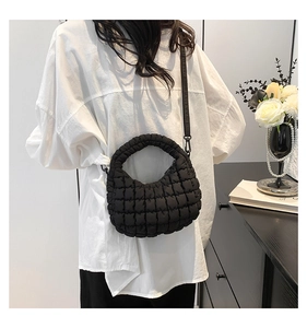 Close-up of black quilted bubble mini tote bag with round handles and crossbody strap
