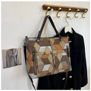 Detail of a color-block patchwork tote bag with crocodile texture on a wooden hook