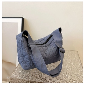 Close-up of dark blue quilted hobo bag featuring diamond stitching and wide shoulder strap