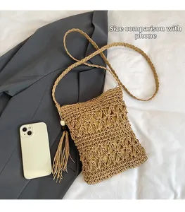 Detail view of khaki woven straw bag with floral cutouts and tassel for size comparison