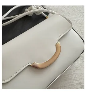 Detail of white PU leather bag featuring a gold half-moon metal buckle and knotted strap
