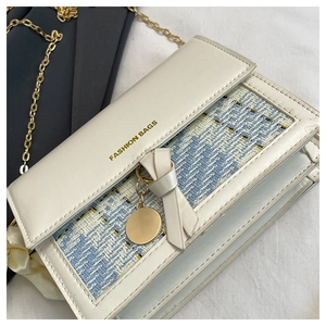 Detail of cream PU leather and light blue tweed crossbody bag with golden chain and bow
