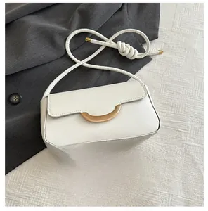 Detail of white PU leather crossbody bag with gold metal buckle and woven rope strap
