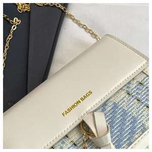 Detail of tweed and cream leather mini bag with gold chain and bow decoration