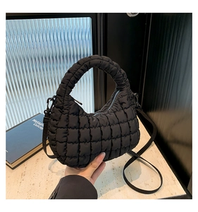 Detail of black quilted nylon crescent tote bag showing textured stitching and crossbody strap