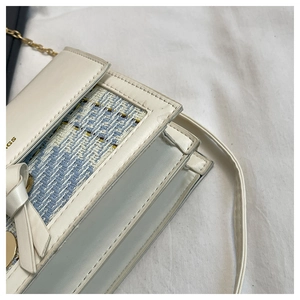 Detail of tweed and leather flap bag with bow accent and gold chain strap