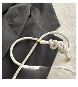 Detailed view of the white woven leather knotted handle with elegant gold metal tips