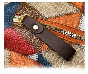 Macro shot of colorful faux python and pebbled leather bag with a gold zipper detail
