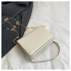 Detail of off-white rectangle flap bag with gold chain and silk bow accessory