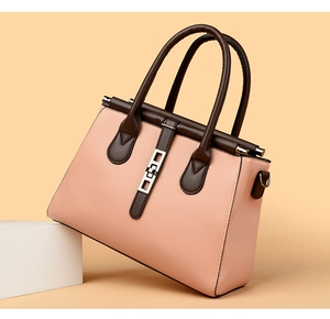Close-up of pink litchi grain leather bag with brown handles and gold metal hardware