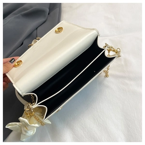 Detail view of white lychee leather bag with dual compartments and golden chain strap