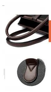Detail view of reinforced stitching on the litchi texture handle of the handbag
