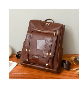 Detailed view of dark brown leather backpack with gold zippers and hardware on wood