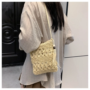 Détail du motif floral ajouré tissé main sur le sac bandoulière en paille beige