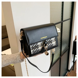 Close-up of black leather and tweed crossbody bag with gold chain and fashion lettering