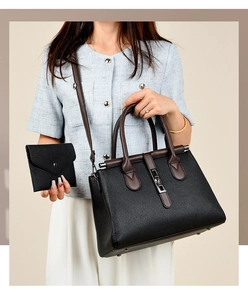 Detail of black lychee leather handbag with dark brown handles and mini envelope wallet