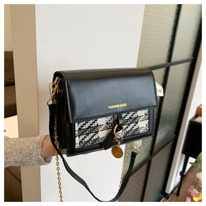 Detail of black crossbody bag with houndstooth pattern and golden ring lock