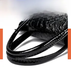 Detailed close-up of comfortable handles and crocodile pattern on black handbag