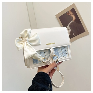 Detail of white leather shoulder bag with blue tweed flap and large satin bow decoration