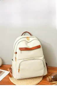 Detailed view of cream white backpack featuring litchi grain PU leather and gold zippers