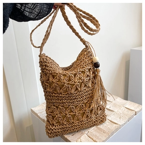 Détail du sac bandoulière en paille tressée avec motifs étoiles et pompons décoratifs