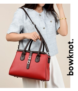 Detail of red pebbled leather handbag with brown handles and silver metallic buckle