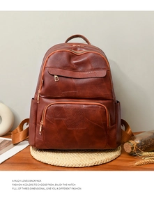 Detailed view of the brown leather backpack featuring patchwork stitching and zip pockets