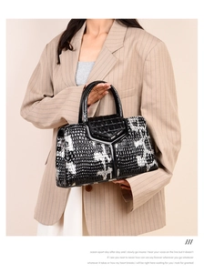Detail of black crocodile texture handbag with white ink splash pattern and Y-shaped strap