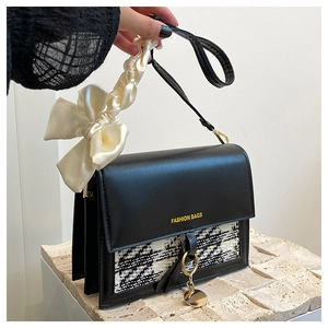 Detail of tweed flap shoulder bag featuring a cream satin bow and gold metal charms