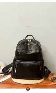 Close-up of black PU leather patchwork backpack with gold zippers on a rustic wooden table