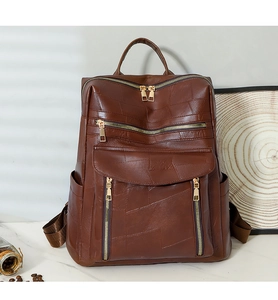 Détail d'un sac à dos vintage marron avec patchwork en cuir et zips dorés élégants