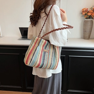Détail d'un sac cabas en paille tissée à rayures multicolores et étiquette en cuir
