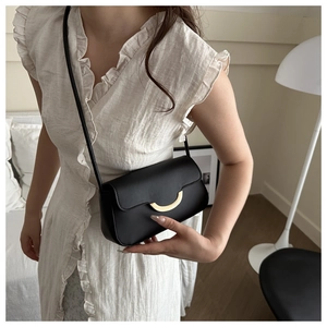 Chic black shoulder bag with gold crescent buckle shown on model in home setting