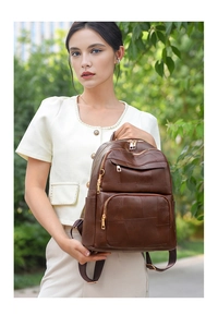 Detailed view of brown leather backpack with geometric texture and gold metal zippers