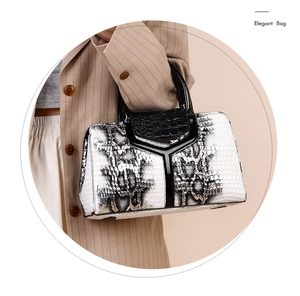 Detail of elegant snakeskin pattern handbag with polished metal decor and black handle