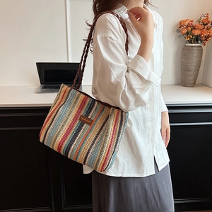 Détail du sac cabas en paille à rayures multicolores avec bandoulière et écusson en cuir