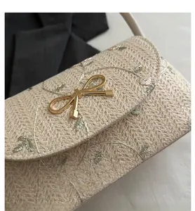 Detailed embroidery of pink and green flowers on a beige woven shoulder bag