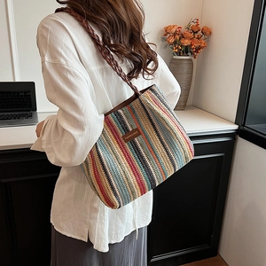 Détail du sac cabas en paille à rayures montrant la texture et l'étiquette en cuir