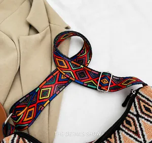 Detail of adjustable woven shoulder strap with geometric ethnic pattern and silver metal buckle