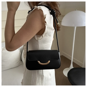 Detail of a black leather underarm bag featuring a crescent-shaped gold metal buckle