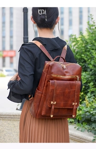 Detail of vintage brown leather backpack with golden zippers and urban street background