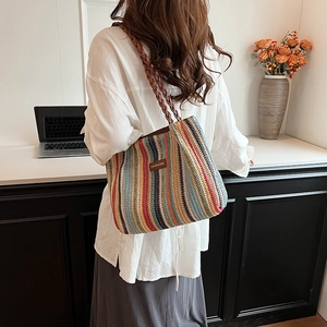 Détail d'un sac cabas en paille tissée rayé arc-en-ciel avec patch en cuir et bandoulière