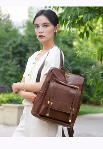 Detail of dark brown faux leather backpack with vintage textures and gold buckles