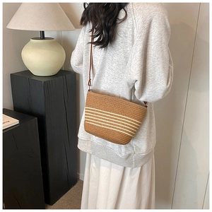 Detail of woven straw crossbody bag with brown stripes for summer beach vacations