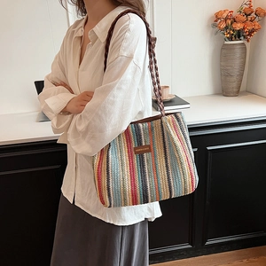Détail d'un grand sac cabas en paille à rayures colorées avec étiquette et bandoulière tissée