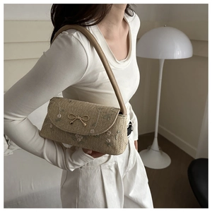 Detail of straw woven shoulder bag with floral embroidery and gold bow clasp
