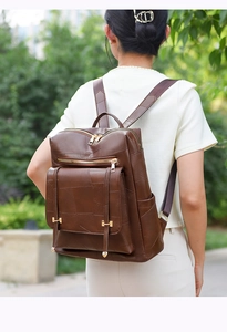 Deep brown backpack with leather texture and multi-pocket design shown on model outdoors
