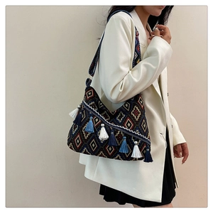 Detailed shot of ethnic embroidered hobo bag with colorful tassels and patterned strap